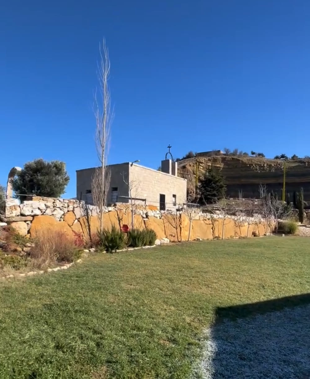 The stone chapel at Tierra del Sol above a dry-stone wall, with the open lawn in front of it.